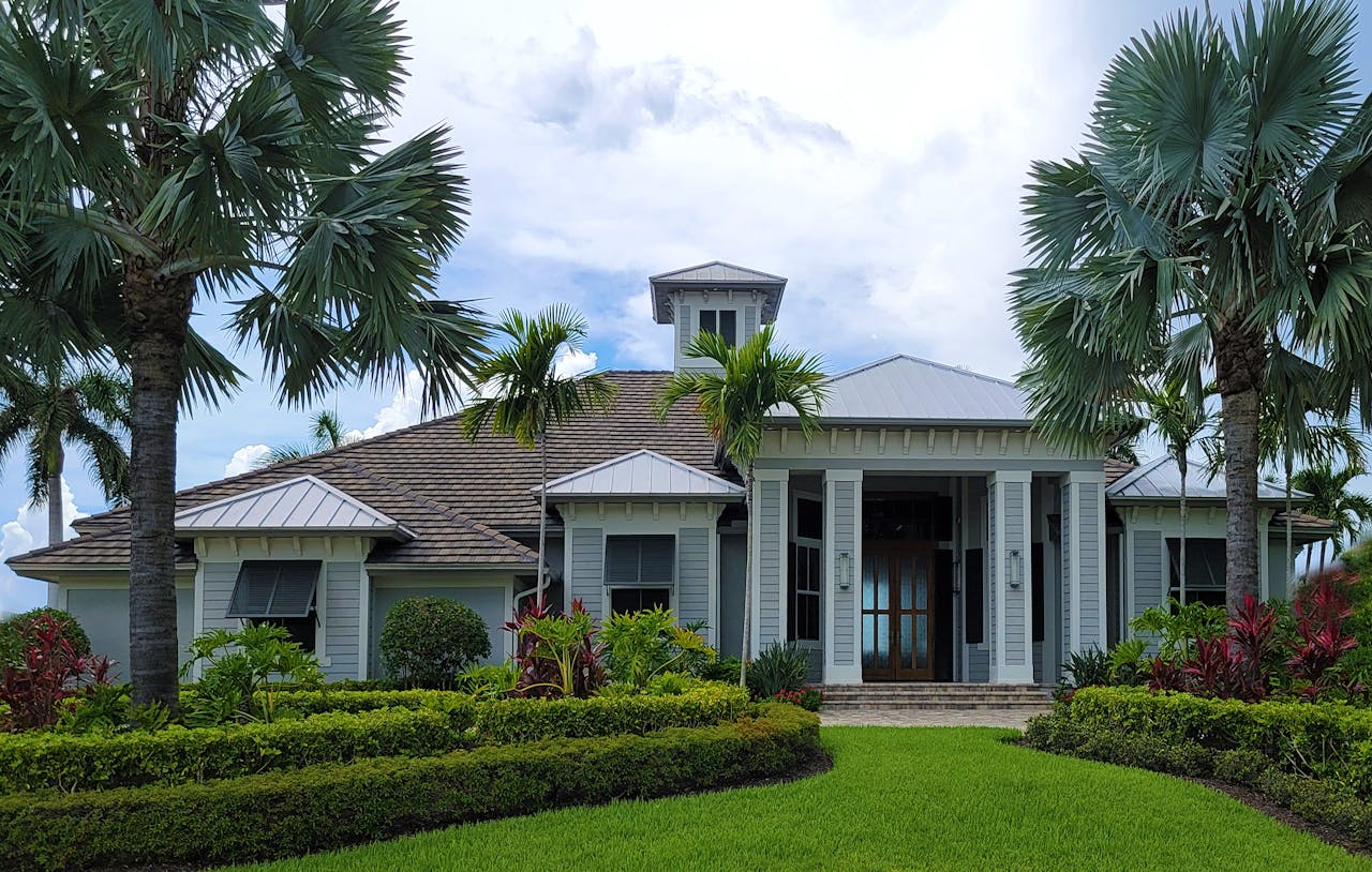 Luxurious modern mansion surrounded by lush greenery and palm trees, ideal for real estate promotion.